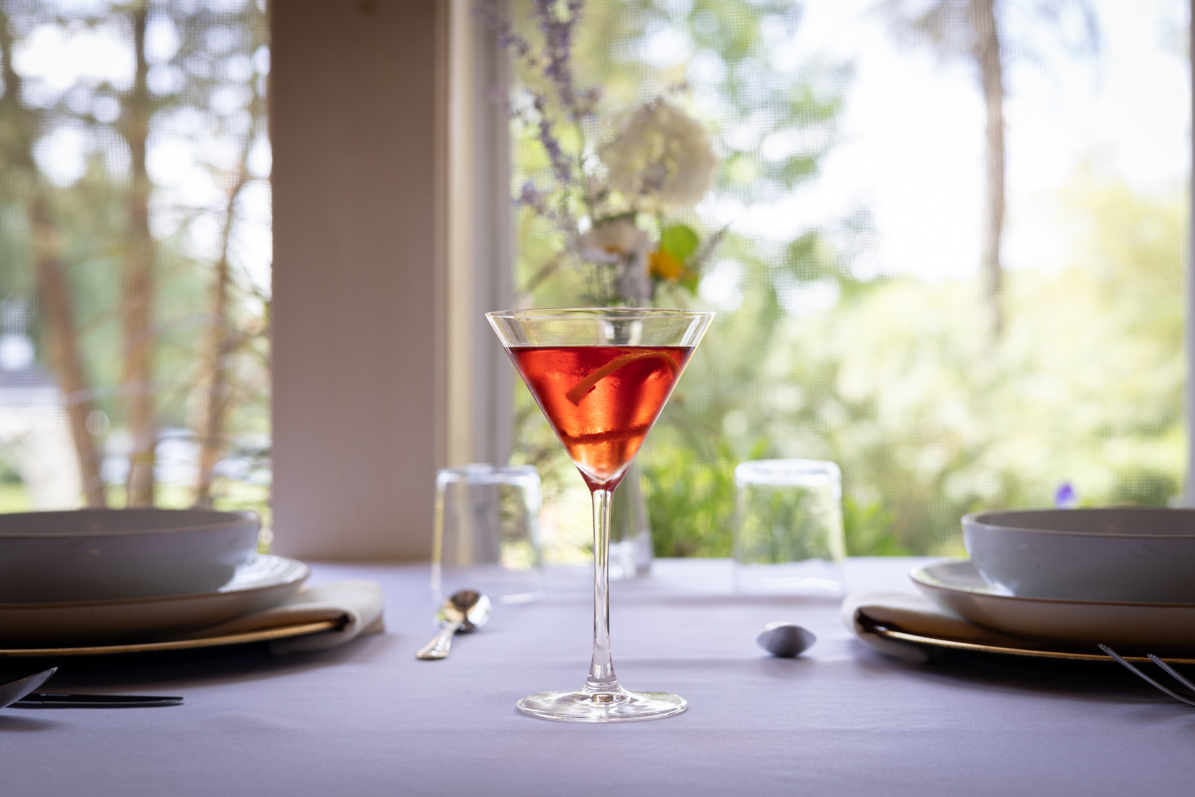 The Small Batch Handcrafted Hibiscus Gin Martini at Hibiscus — a deep ruby martini on a candlelit dining table